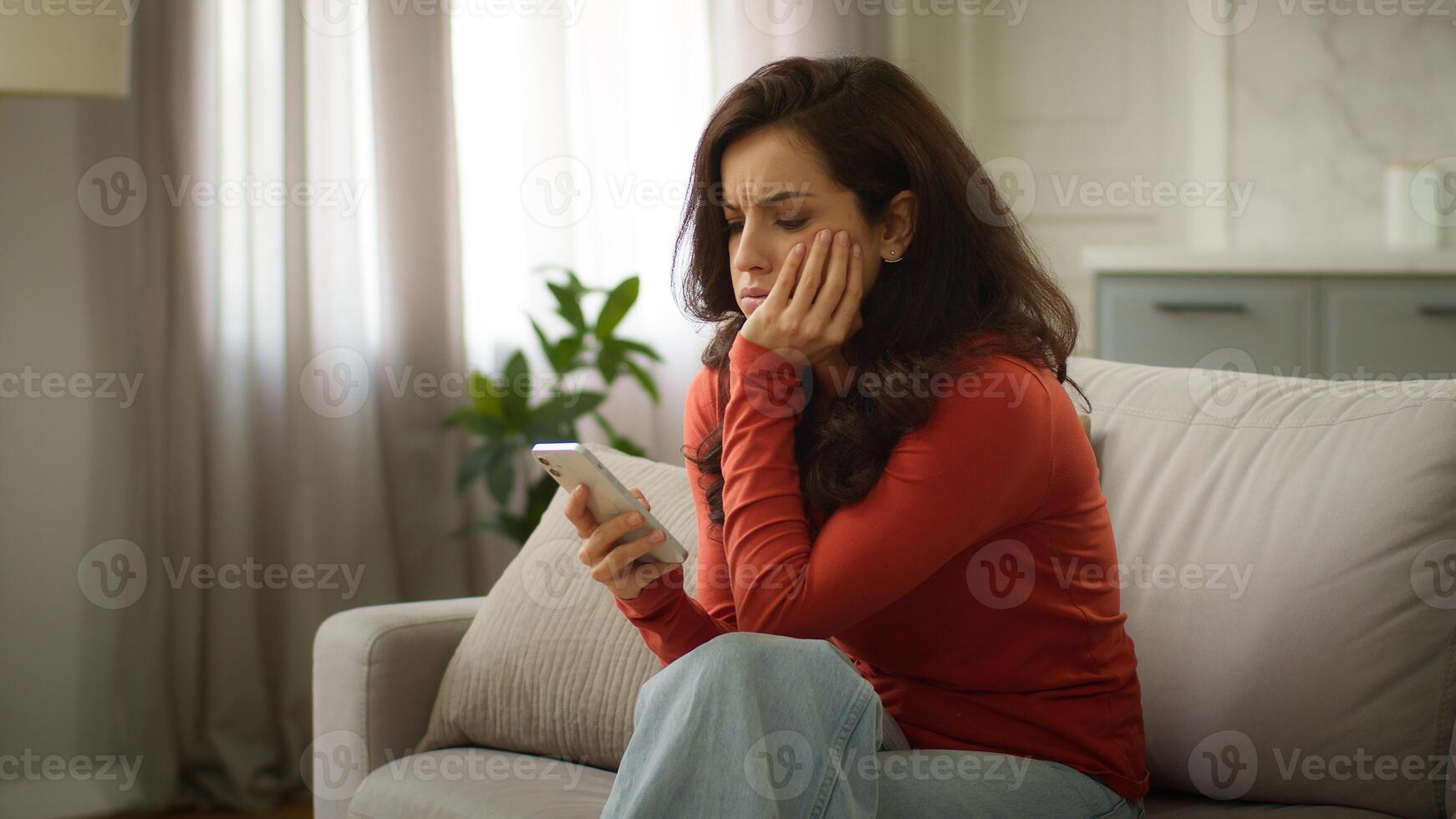 Shocked upset sad Caucasian troubled woman female girl client holding mobile phone cellphone reading bad news negative reaction no connection smartphone error failure losing online game at home couch photo
