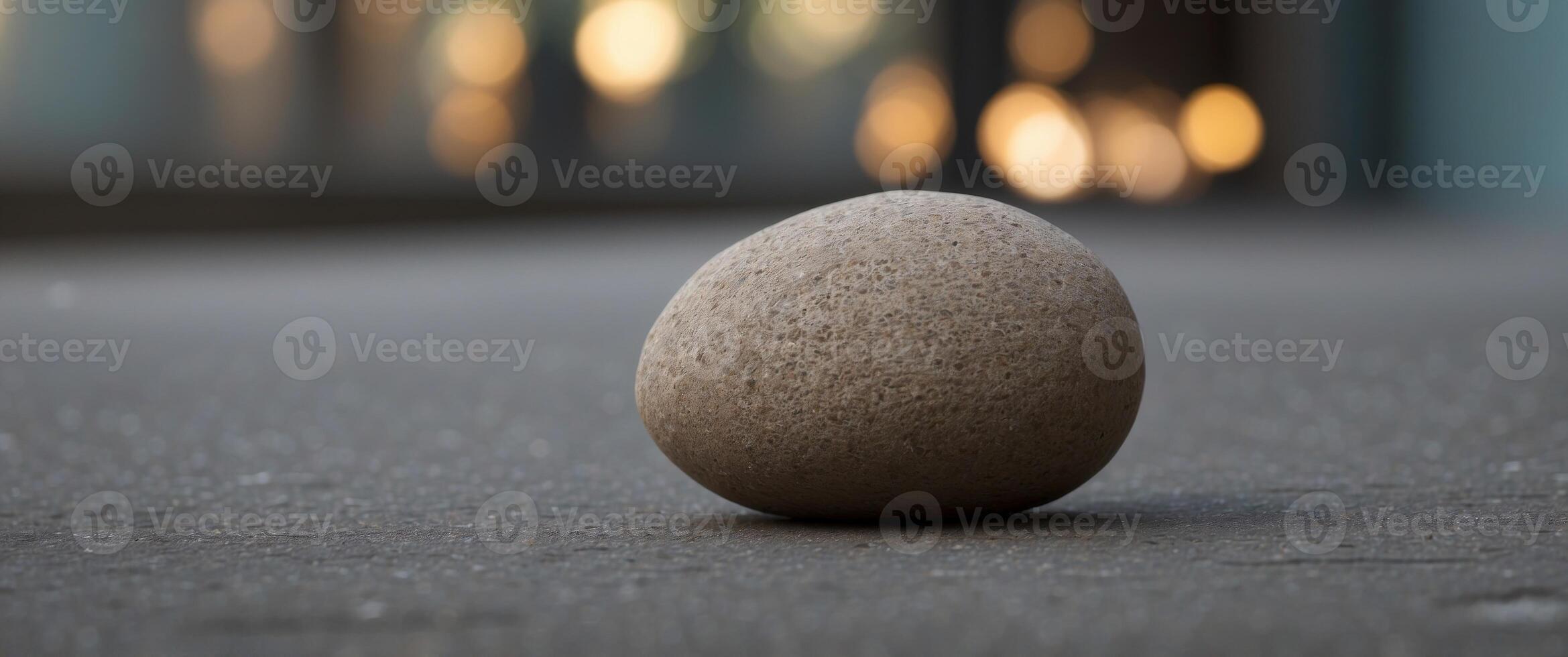 A stone is sitting on a concrete floor in front of a wall. photo