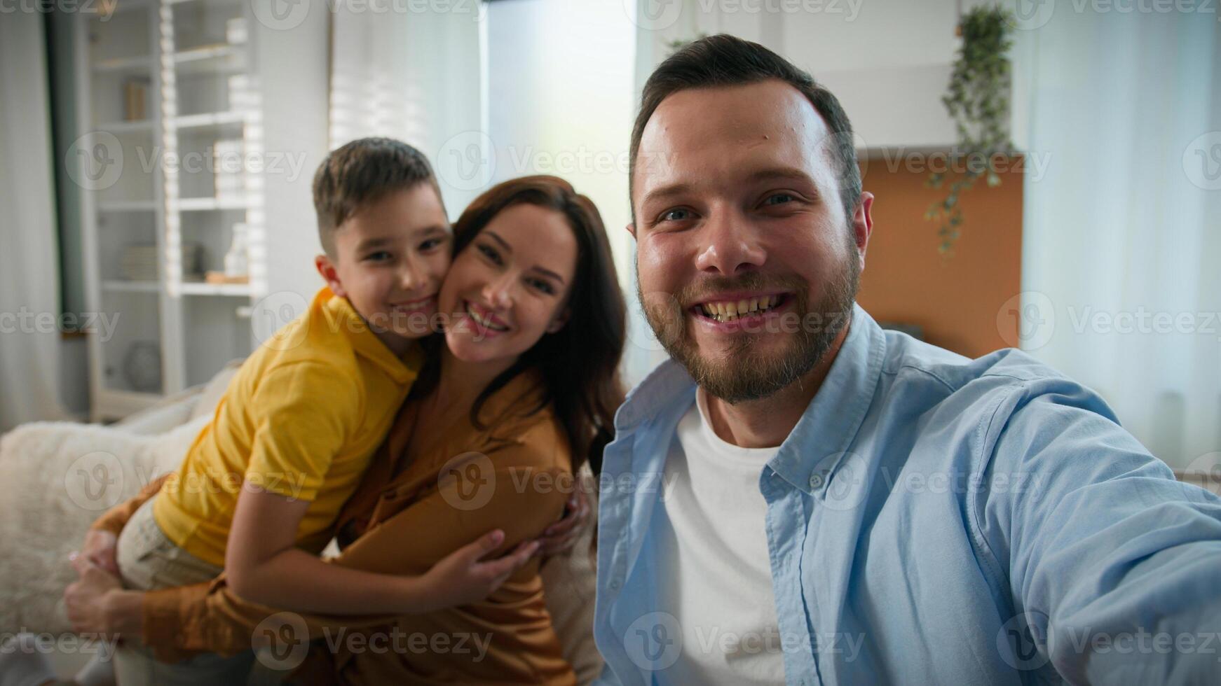 Happy Caucasian family talking on online call wave hello greeting looking at webcam father mother son bloggers recording vlog parents kid boy child communicate together remote on device at home photo