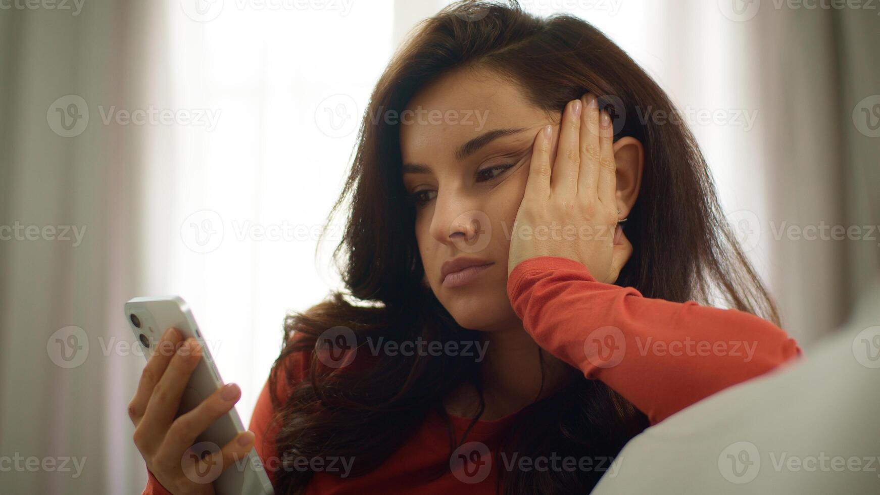 Bored sad Caucasian upset woman lazy female girl unhappy client user scrolling mobile phone smartphone browsing social media online app on couch burnout problems boredom depression indoors home room photo