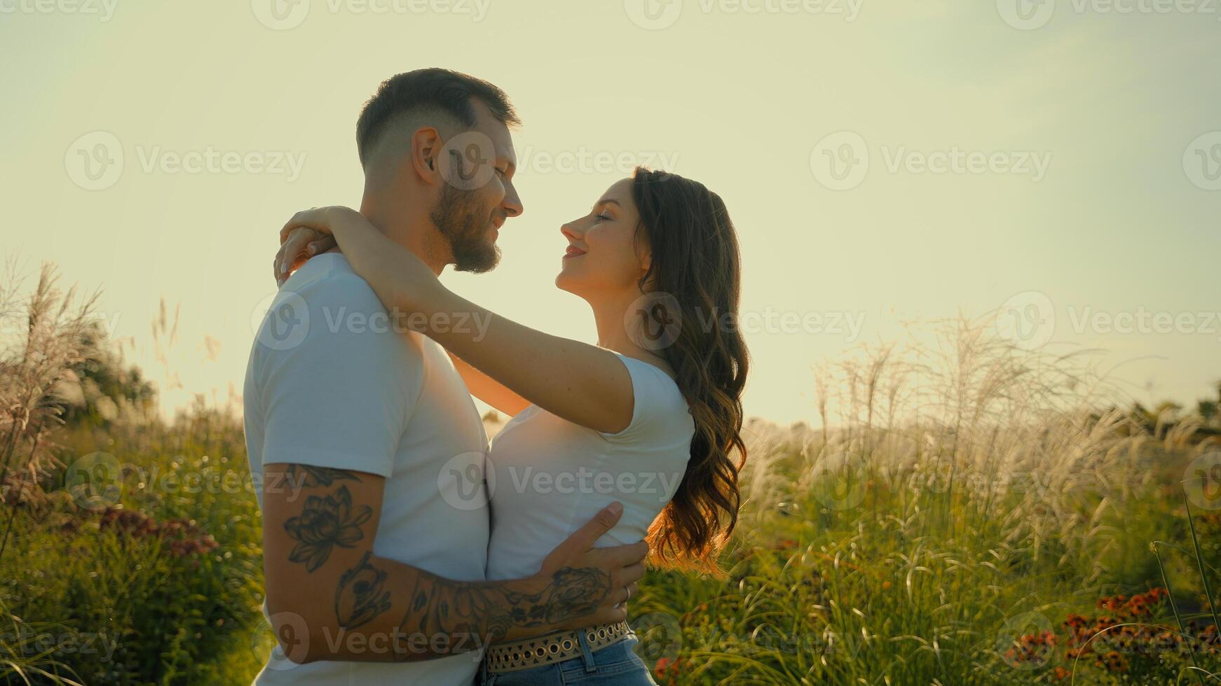 Happy romantic loving Caucasian couple man woman tender family wife husband kiss guy hug girl showing love hugging embracing kissing outdoors deserted wheat field sunrise sunshine dating relationship photo