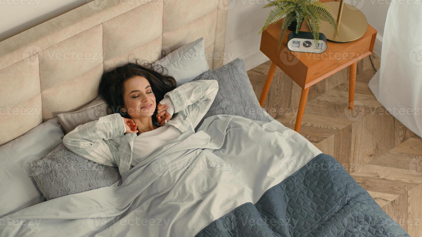 Happy woman stretching lying bed lazy comfortable girl female home hotel rest enjoyment smile good mood relaxed sleepy bedroom satisfaction pleasure weekend glad accommodation awaken daydream mattress photo
