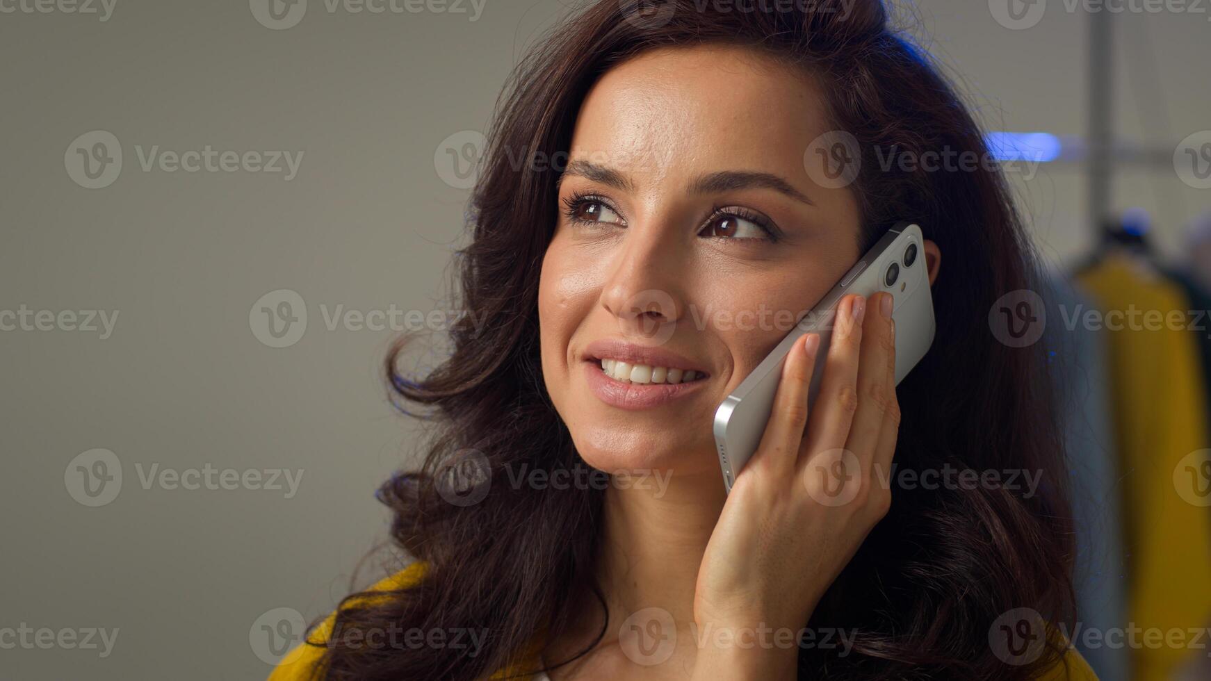 Smiling happy Caucasian woman lady influencer girl answering call talk speaking mobile phone telephone device glad female model discussing sharing good news friendly remote conversation in studio home photo