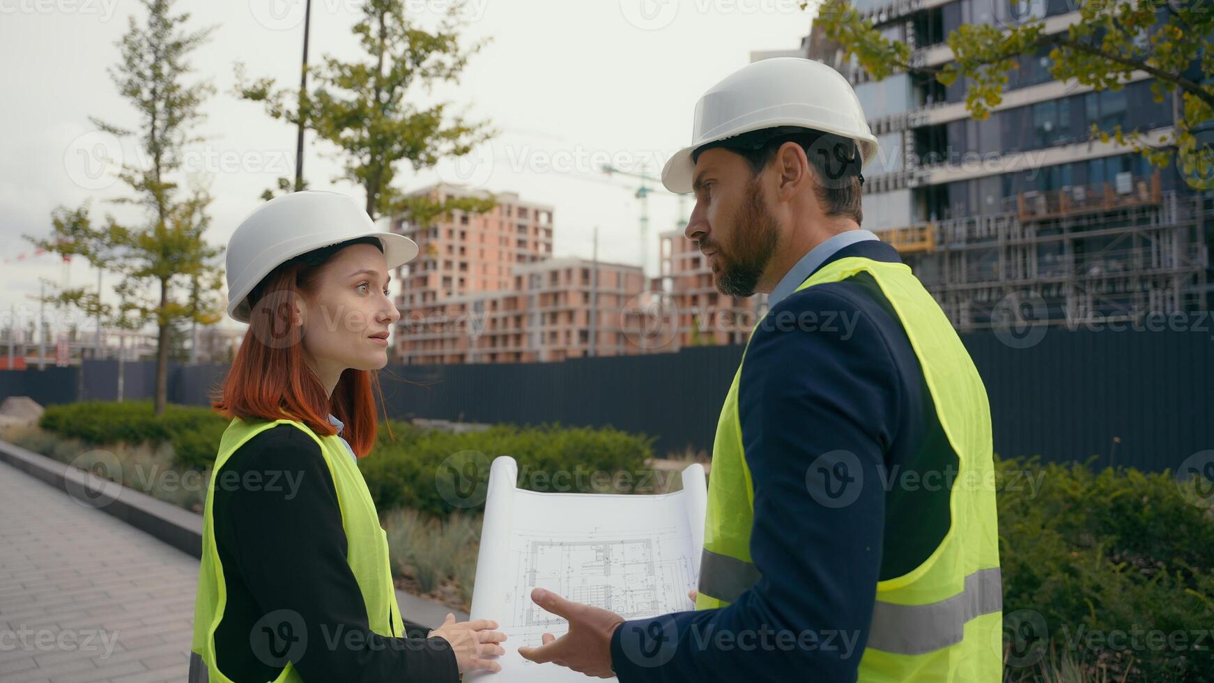 Two contractors civil engineers checking information in blueprint discuss teamwork pointing city buildings project managers planning collaboration construction workers with plan for urban development photo