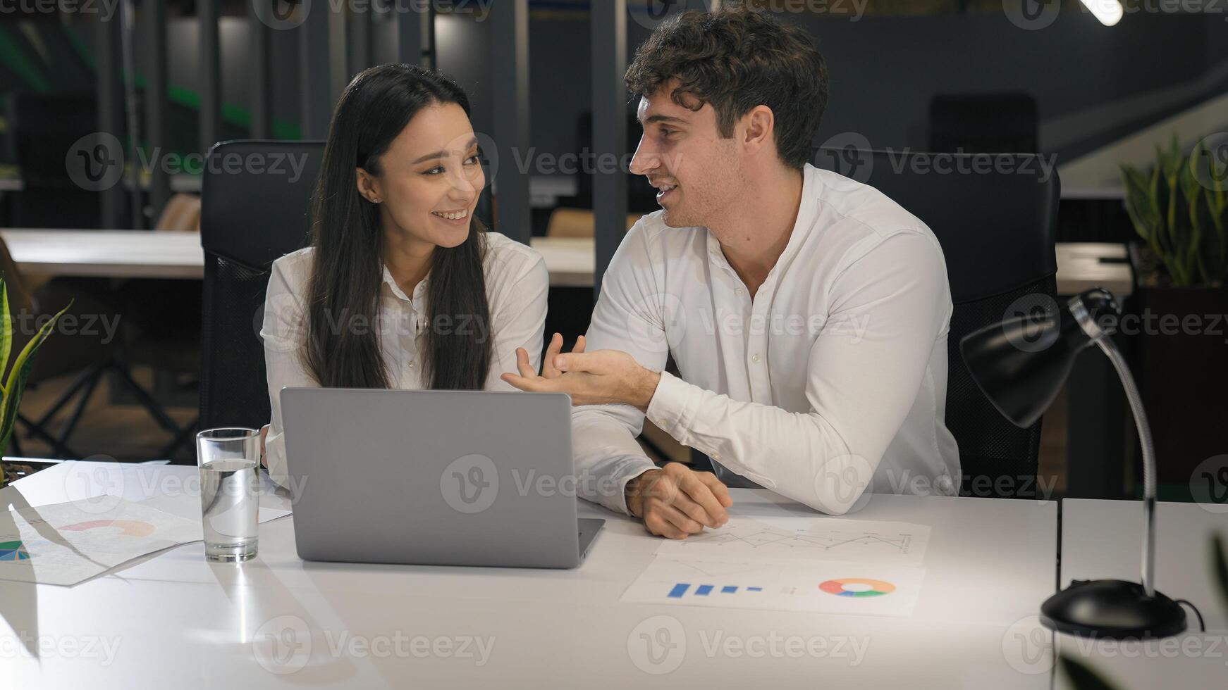 Cheerful Caucasian talking smiling laughing with laptop computer pc in office colleagues male manager and female businesswoman at desk working discussing project together having fun corporate business photo