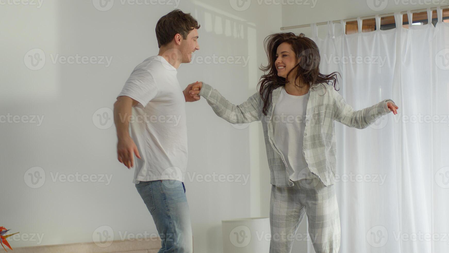 Boyfriend girlfriend man woman jump on bed bedroom holding hands fun enjoyment laugh homeowner happy couple female male active honeymoon leap bounce sweetheart pampering movement energy home together photo