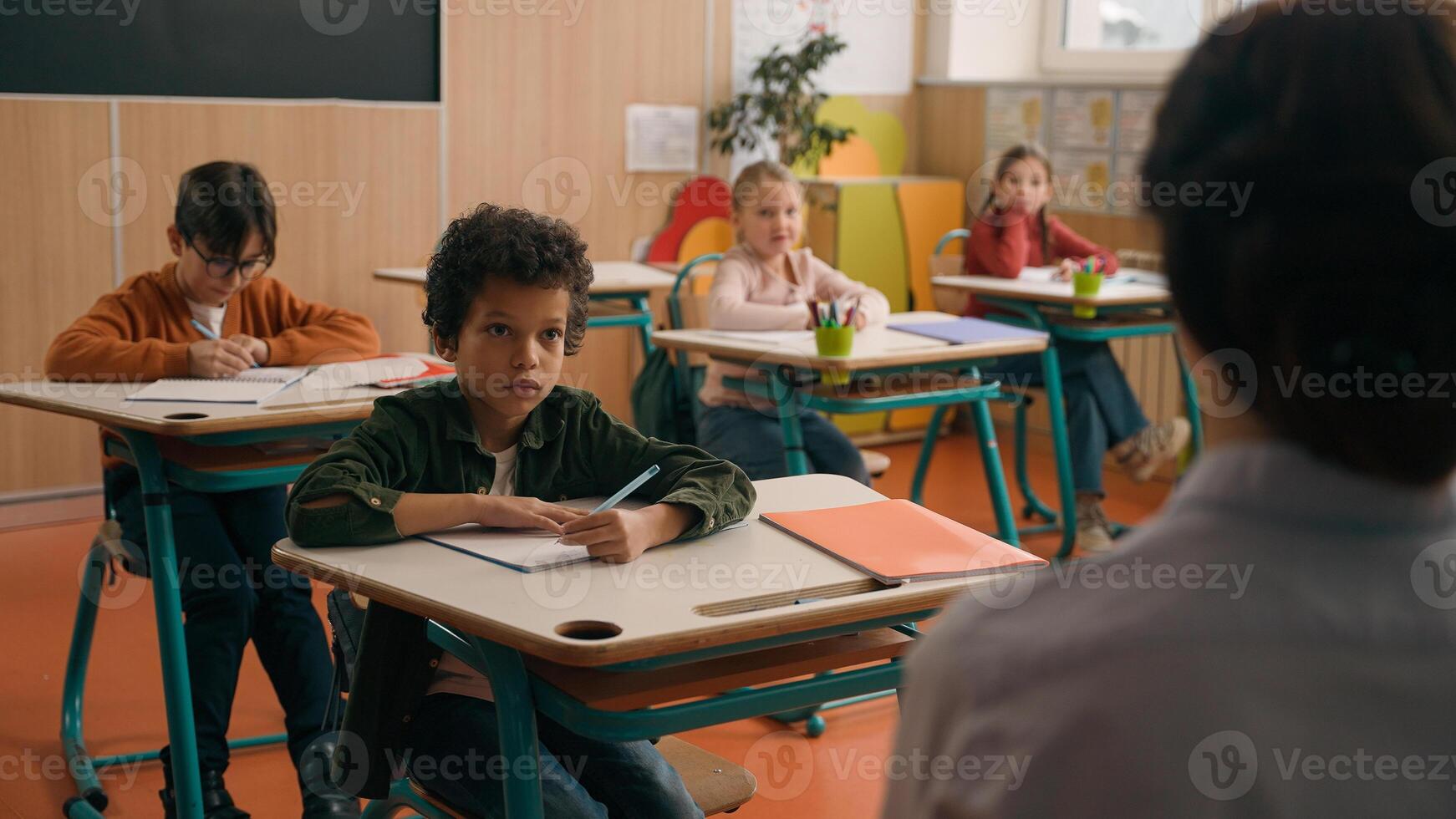 School class lesson group of multiracial diversity multiethnic children kids studying learning rise hands unrecognizable woman teacher back view choose girl answer tutor talking study learn education photo