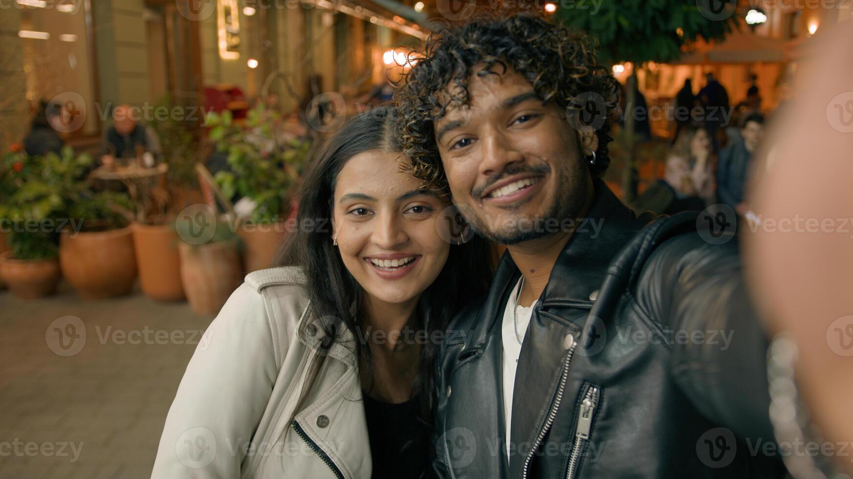 In evening night city happy Indian Arabian couple in love woman man people make selfie photo webcam web camera view travel dating posing photographing picture together relationship vacation adventure