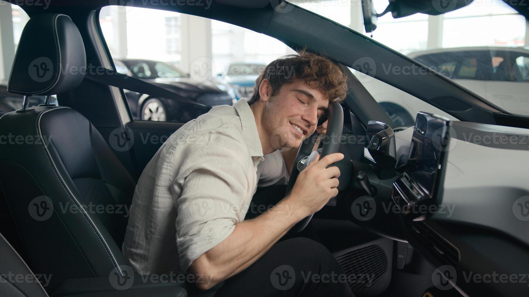 Caucasian client man buyer guy customer male sitting in luxury new car choosing auto visit showroom choose automobile rent test drive buying enjoy vehicle choice embrace hug cuddling wheel steering photo