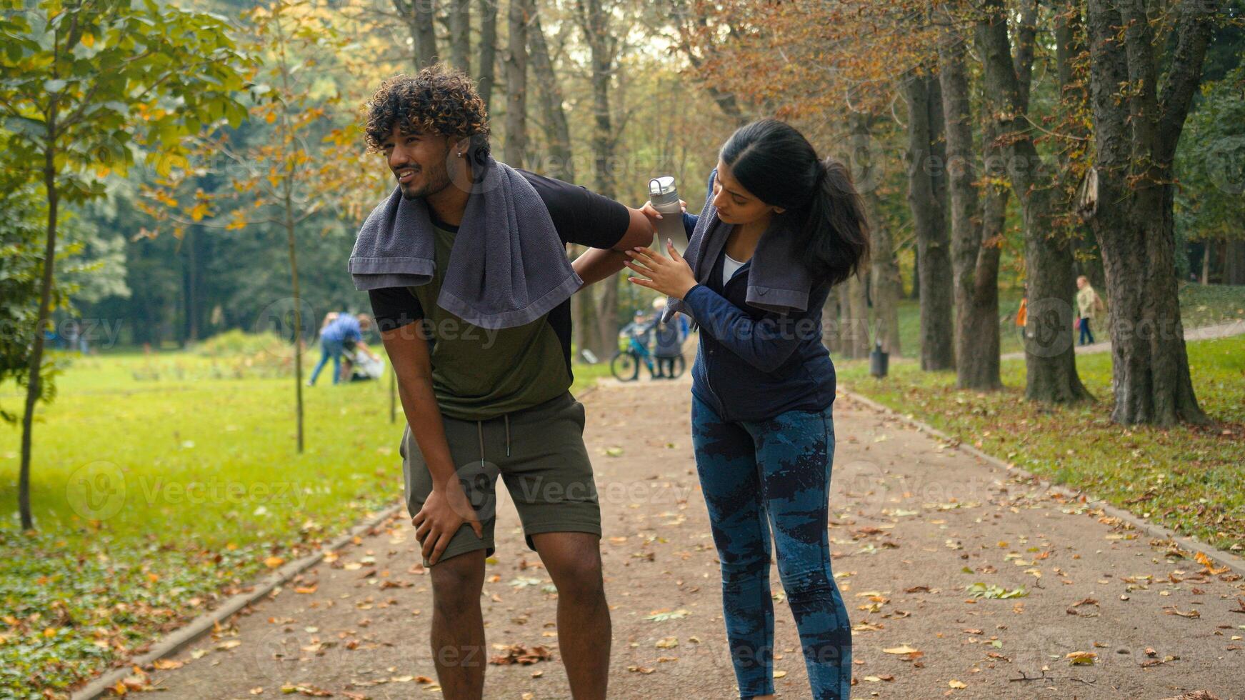 Outdoors in nature park Indian Arabian couple friends man woman stop after cardio fast run jog running man tired exhausted resting feel bad unwell pain ache girl calm support care of guy people sports photo