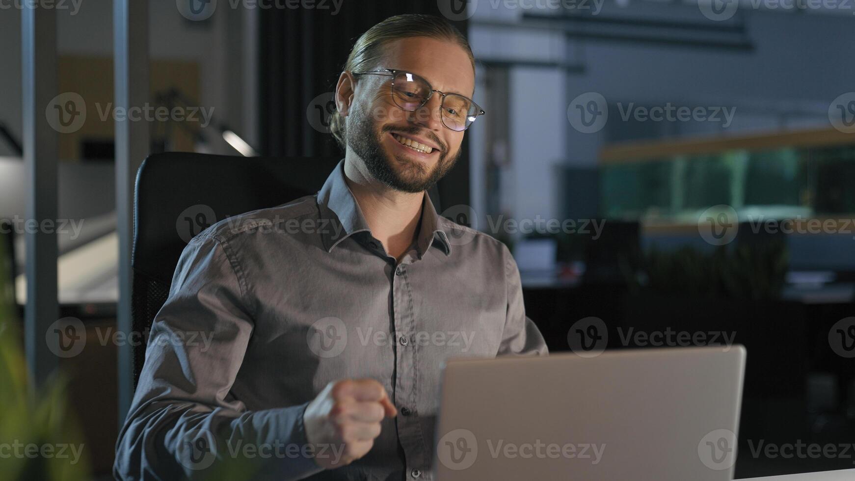 Caucasian emotional ecstatic excited businessman trader salesman business man employer office worker winner at night evening workplace win laptop online good result financial growth achieve success photo