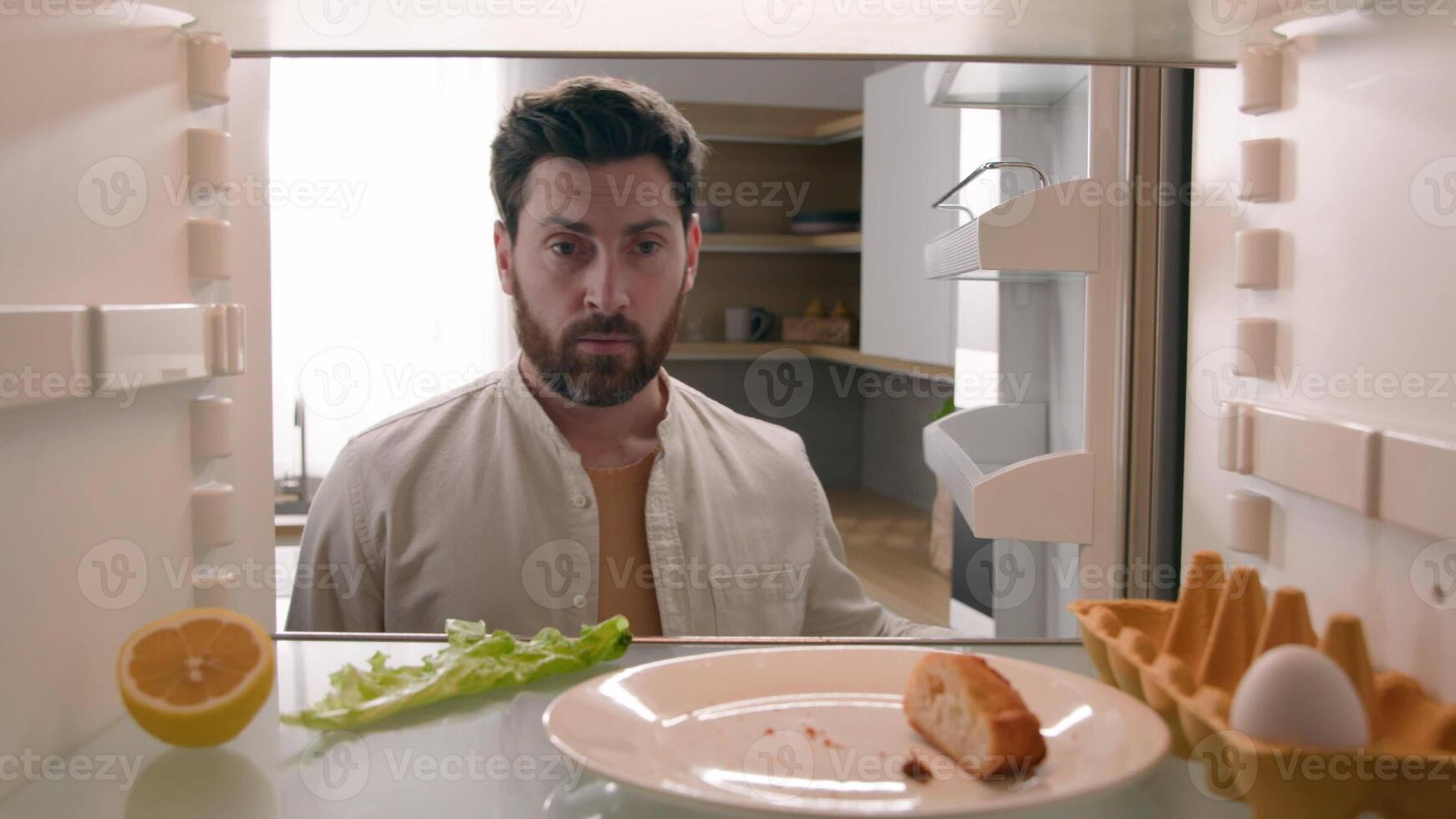POV refrigerator point of view from inside fridge with one egg lettuce half lemon Caucasian confused man adult male guy take empty bottle of orange juice eat bread crumbs food delivery supermarket photo