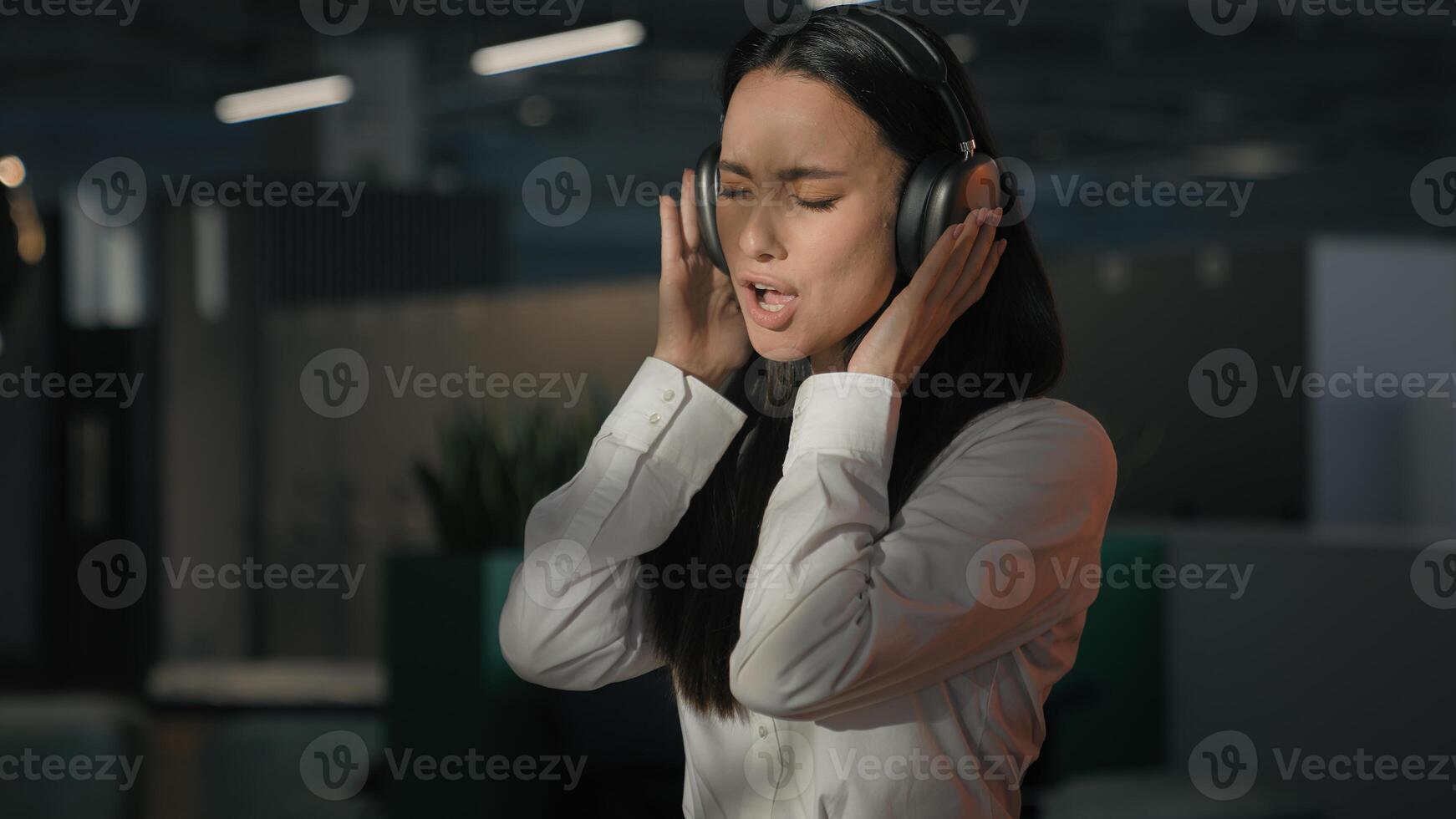 Happy funny carefree Caucasian business woman girl office worker at evening end of work day businesswoman listening music in headphones enjoy song singing dancing pretend drummer playing drum dance photo