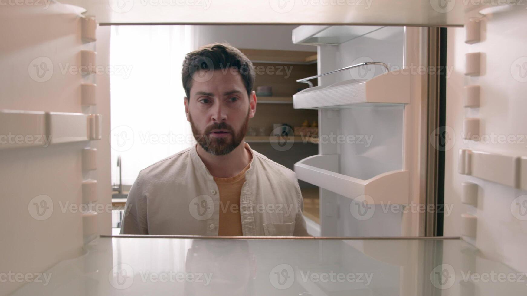 POV point of view from inside refrigerator Caucasian hungry man adult sad upset disappointed male guy looking for good twice open empty fridge no food without products crisis delivery supermarket photo