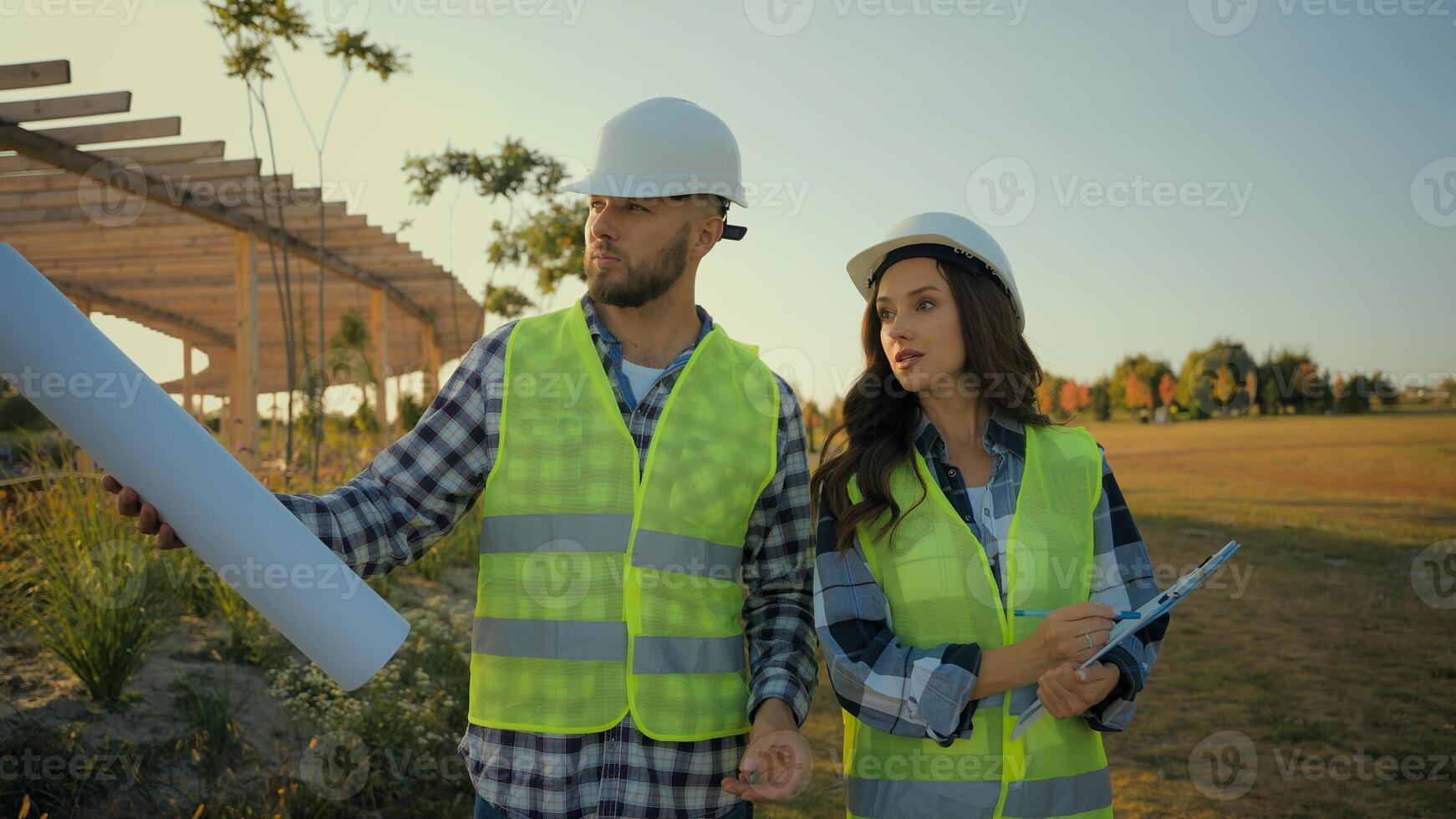Caucasian coworkers architect partnership male man businessman engineer hold blueprint explaining talk female businesswoman inspector woman writing clipboard report pointing finger project scheme park photo