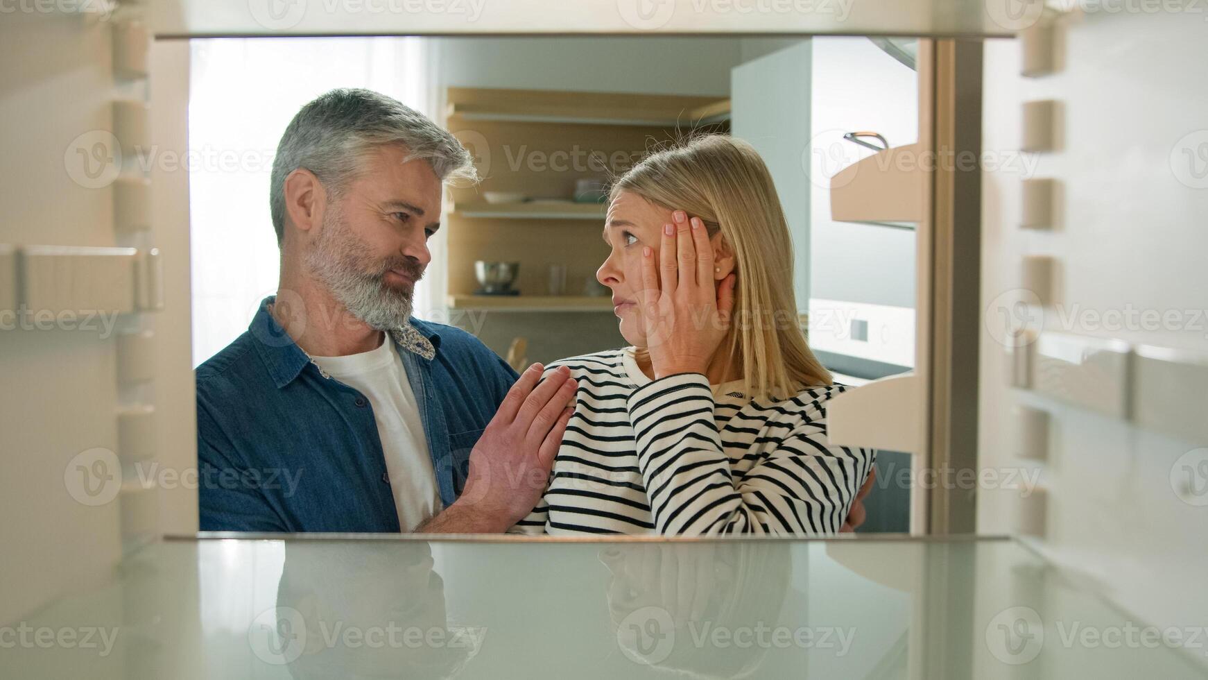 Point of view POV from inside refrigerator Caucasian adult family mature couple middle-aged man woman open empty fridge have nothing to eat sad upset with poor poverty unemployment starvation hunger photo