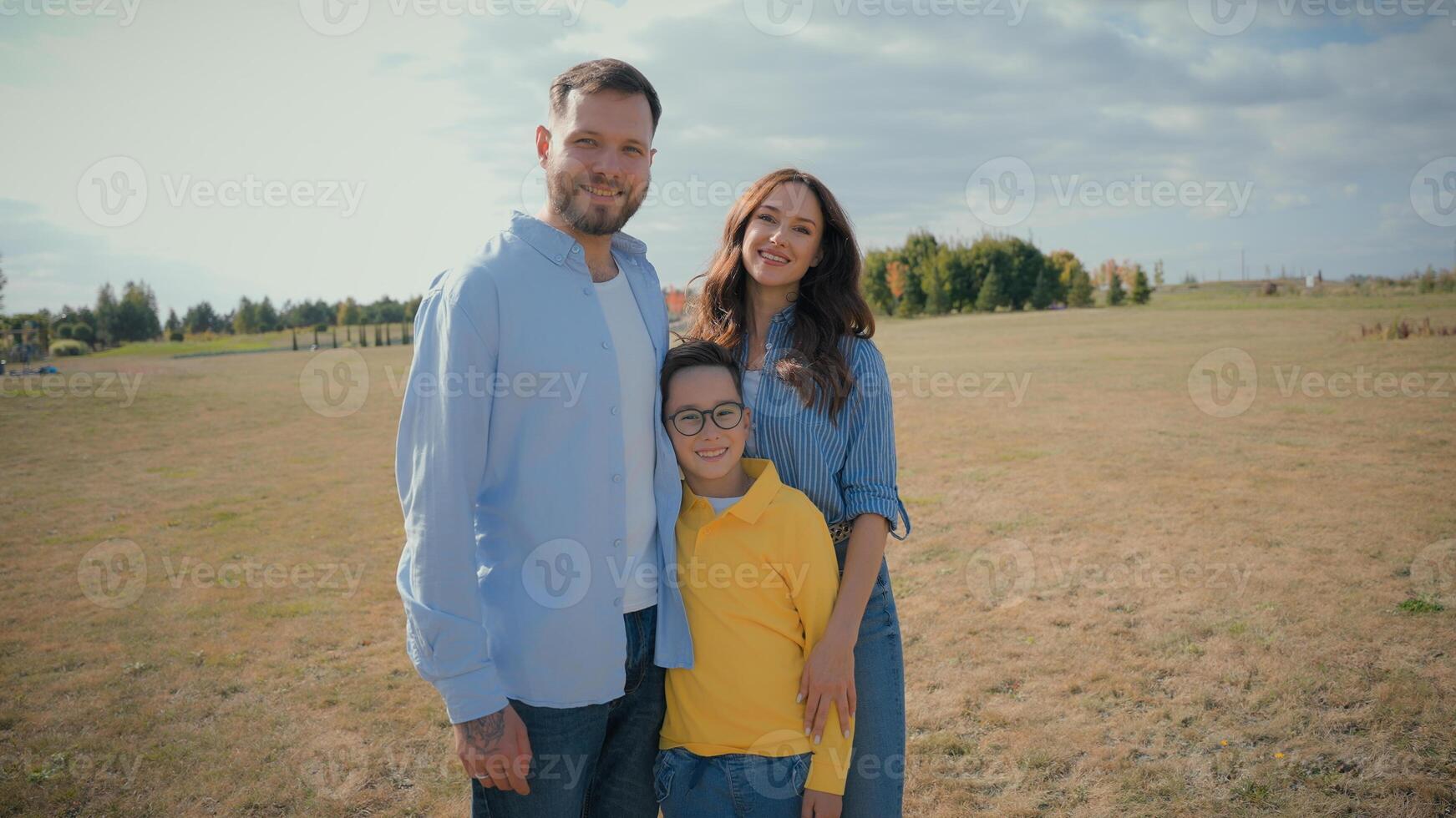 Happy Caucasian farmers family portrait smiling married father mother son little kid child boy hugging together outside countryside field. Agronomy ecology parenting enjoy relaxation fresh air nature photo