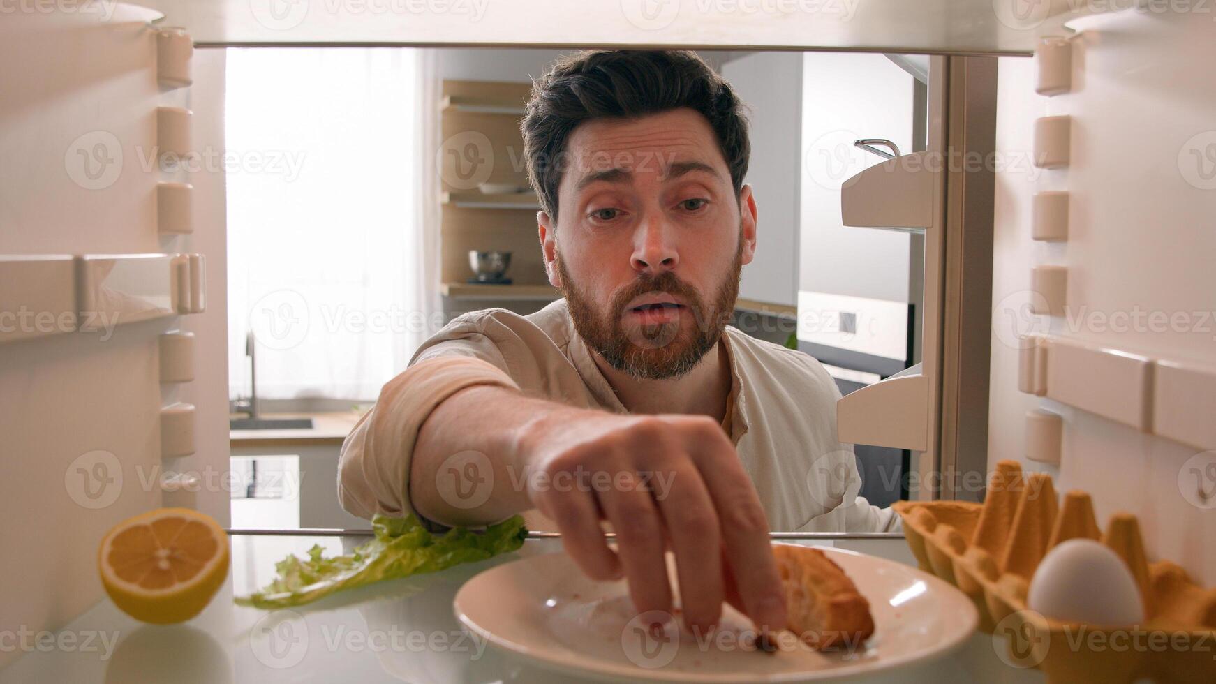 POV point of view from inside refrigerator Caucasian hungry adult man need meal products empty fridge with junk half lemon, lettuce leaf, one egg eating bread crumbs food delivery unemployment crisis photo