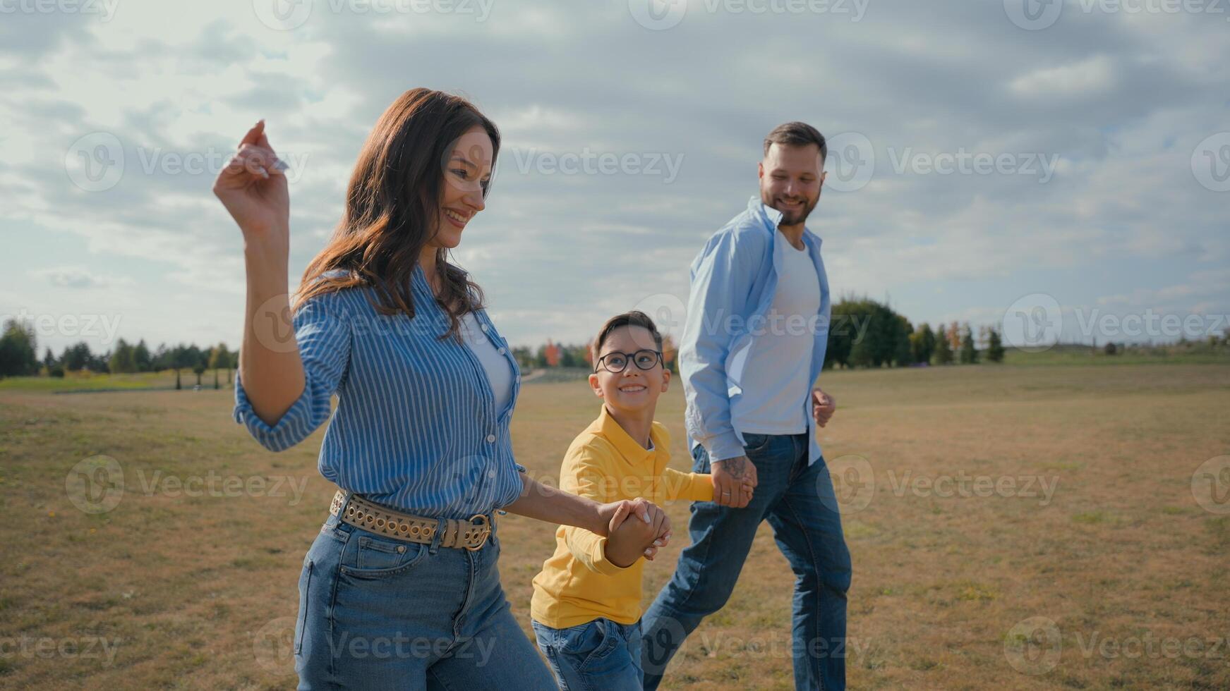 Happy European family smiling laughing man woman couple little boy son kid running outside nature countryside meadow mom dad child holding hand run rural field happiness joy parenting custody adoption photo