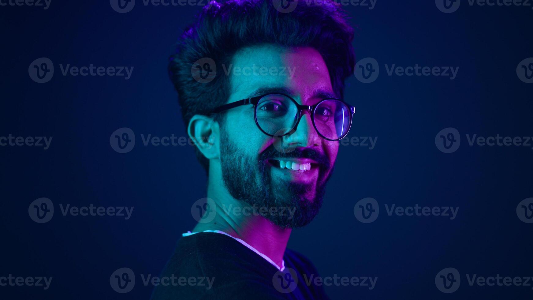 Portrait Indian man standing in profile side view turn to camera smiling toothy happy guy developer coding smile computer internet technology hacker Arabian male neon ultraviolet high-tech cyberspace photo