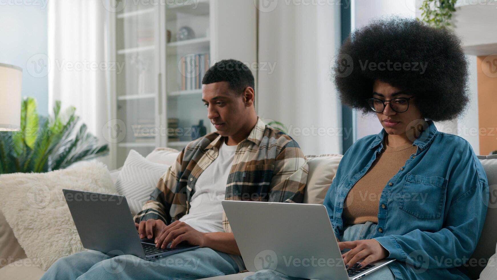 African American gadget addict couple internet addicted husband and wife social media virtual game addiction man and woman working using two laptops play with computers at home relationship problem photo