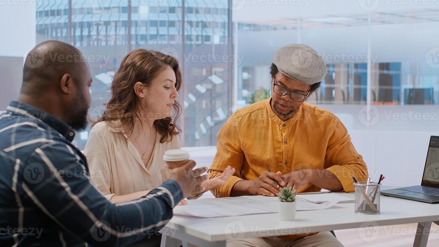 Client and realtor studying architectural plans for the property layout, evaluating investment opportunity at the end of an office tour. Studying blueprints during a meeting with salesman. Camera B. photo