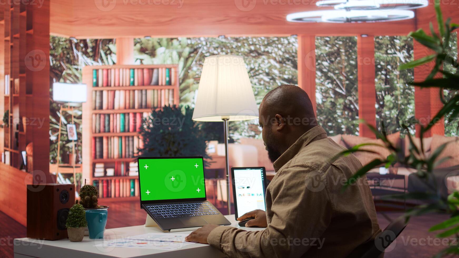 Entrepreneur examines financial statistics next to green screen at home desk, expert adviser calculating budget balance in order to expand business activity. Economic startup situation. Camera B. photo