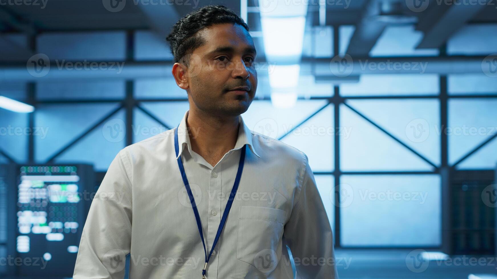 Admin walking amidst server rows, looking to ensure optimal performance and reliability by implement and managing gear. IT staff member in data center overseeing high tech facility, camera A photo