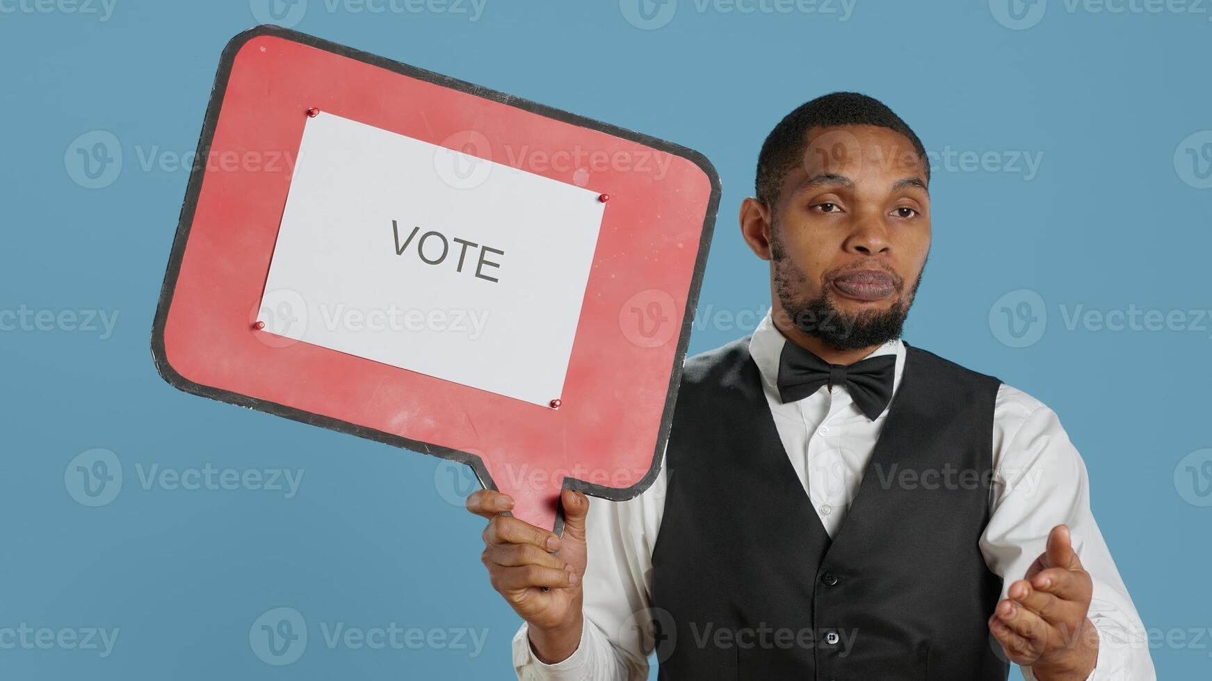 Hospitality industry worker shows speech bubble with political message, urging people to vote with cardboard sign advertisement. Hotel porter employee holds icon with commercial ad. Camera A. photo