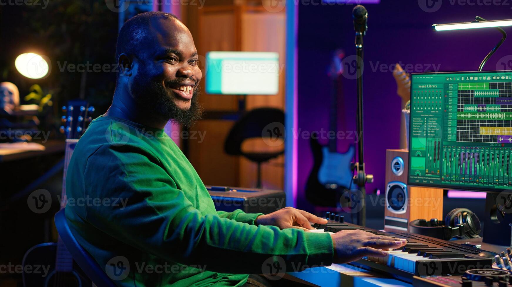 Male artist producing music on electronic piano keyboard in home studio. Sound engineer playing MIDI controller, recording and composing a soundtrack with acoustic tools and gear. Camera A. photo