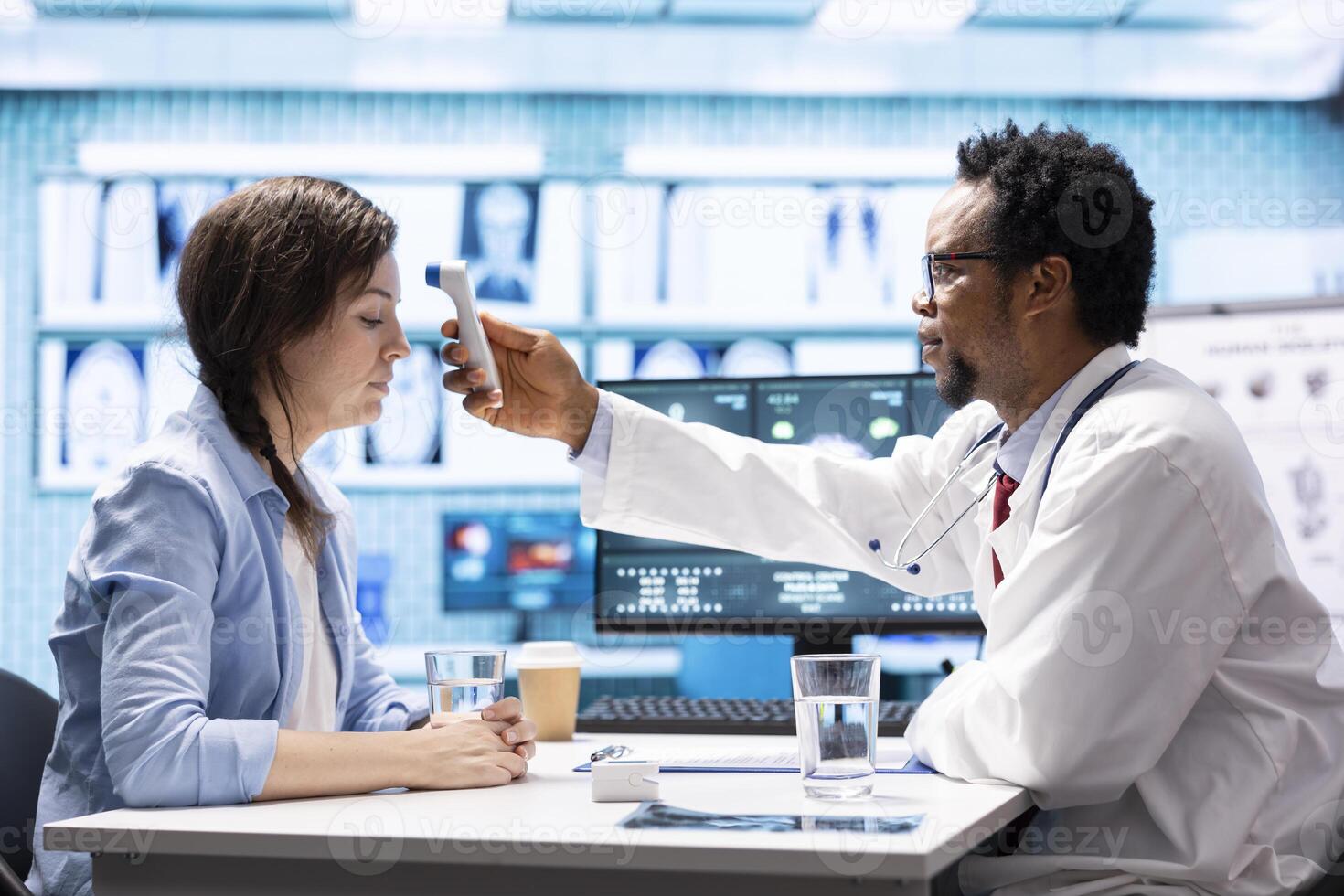 General practitioner using a thermometer to measure fever on a female patient, doing a check up visit examination with modern medical tools. Doctor specialist checking temperature on a woman. photo