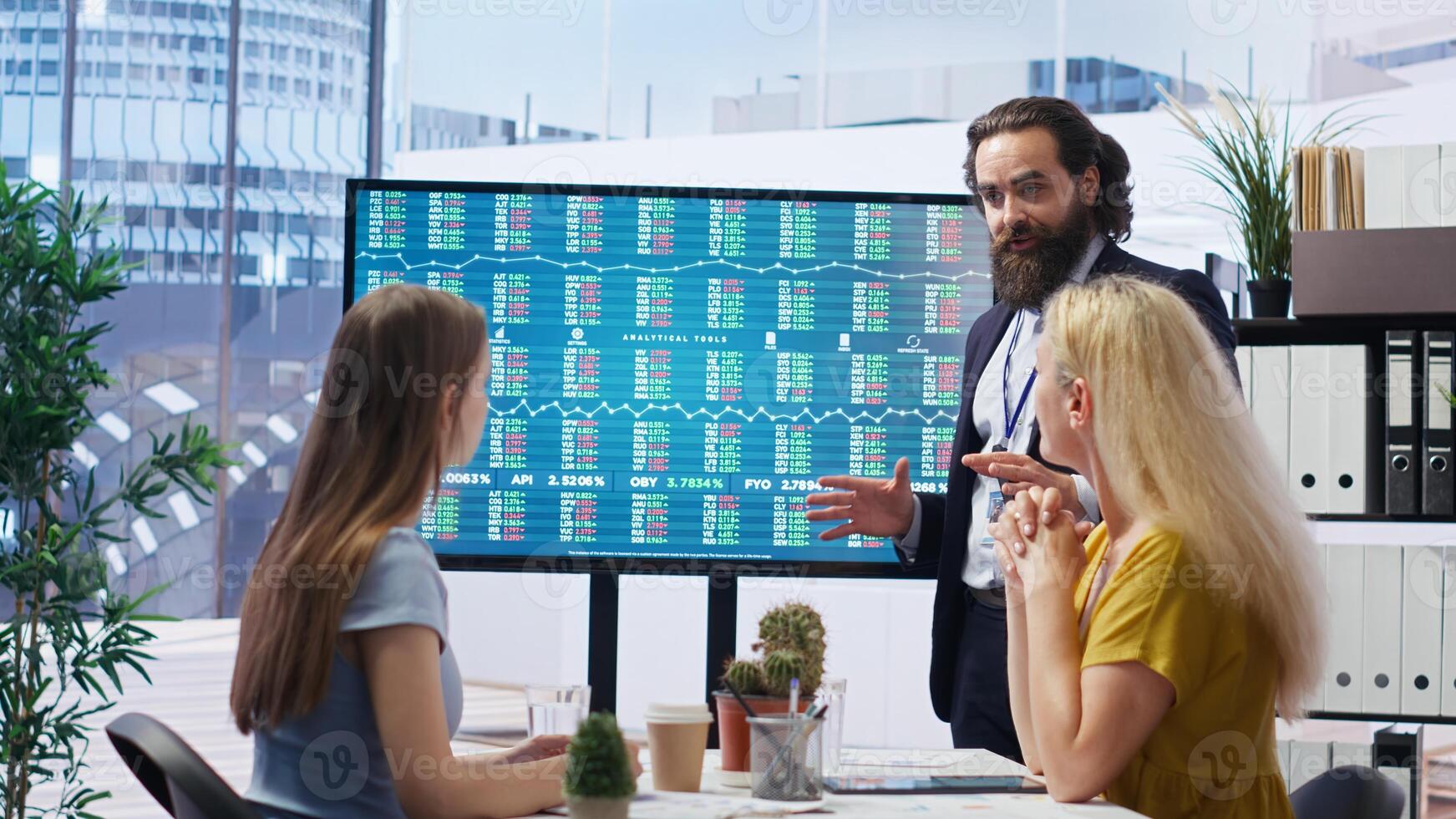 Broker investor in office offering financial advice to clients, looking at stock exchange volatility on big screen. Financial advisor analyzing market shares growth with mother and daughter, camera B photo