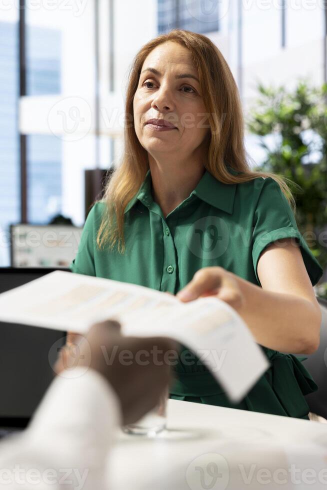 HR worker handing out contract to man after ensuing his qualifications align with company expectations. Recruiter giving forms to fill to applicant after being happy with previous work resume photo
