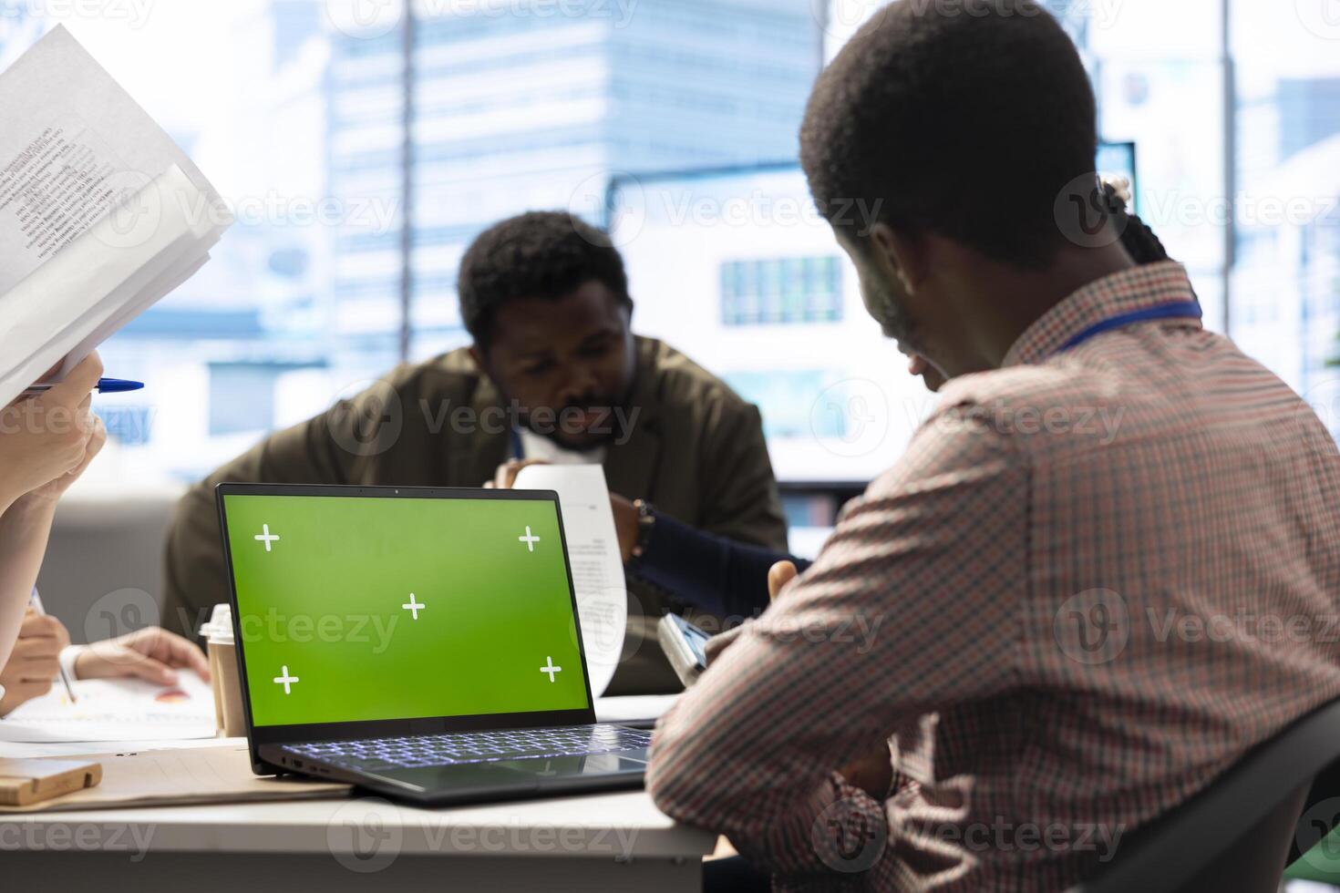 Diverse team of employees using mockup copy space screen on gadget, discussing ways to increase the company budget. Business experts preparing for a presentation in a boardroom meeting. photo