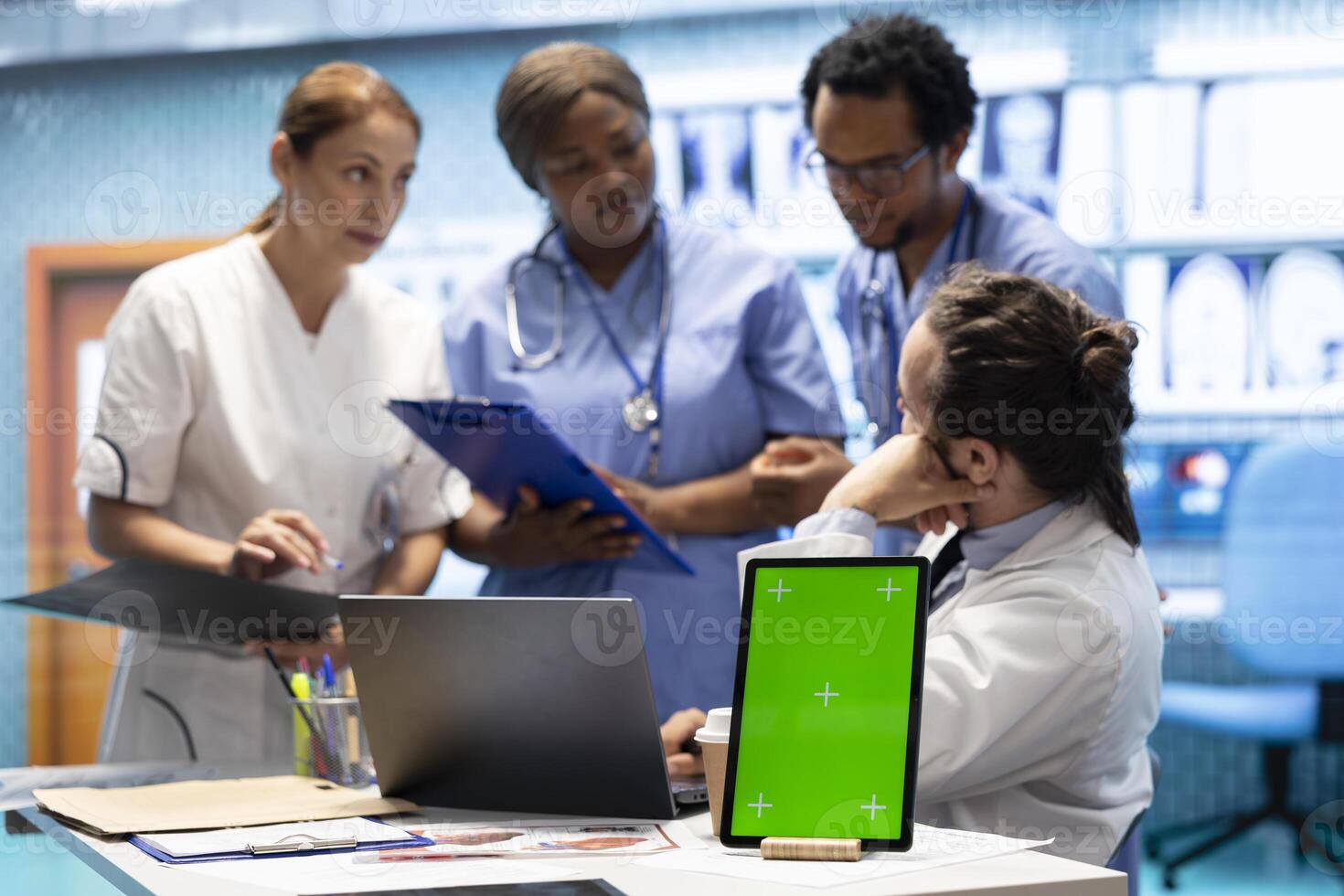 Group of doctors consulting hospital records next to chroma key display, using x ray test results to examine the diagnosis. Diverse experts meeting at private clinic to provide a treatment plan. photo