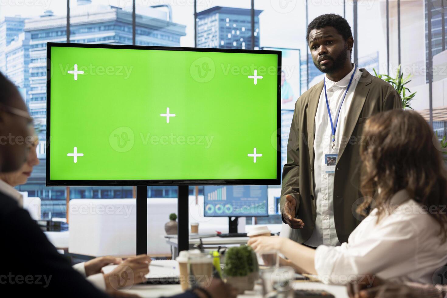 Diverse team of business associates looking at a mockup chroma key screen during an executive board meeting, utilizing smart technology. Enterprise staff develop effective business strategies. photo