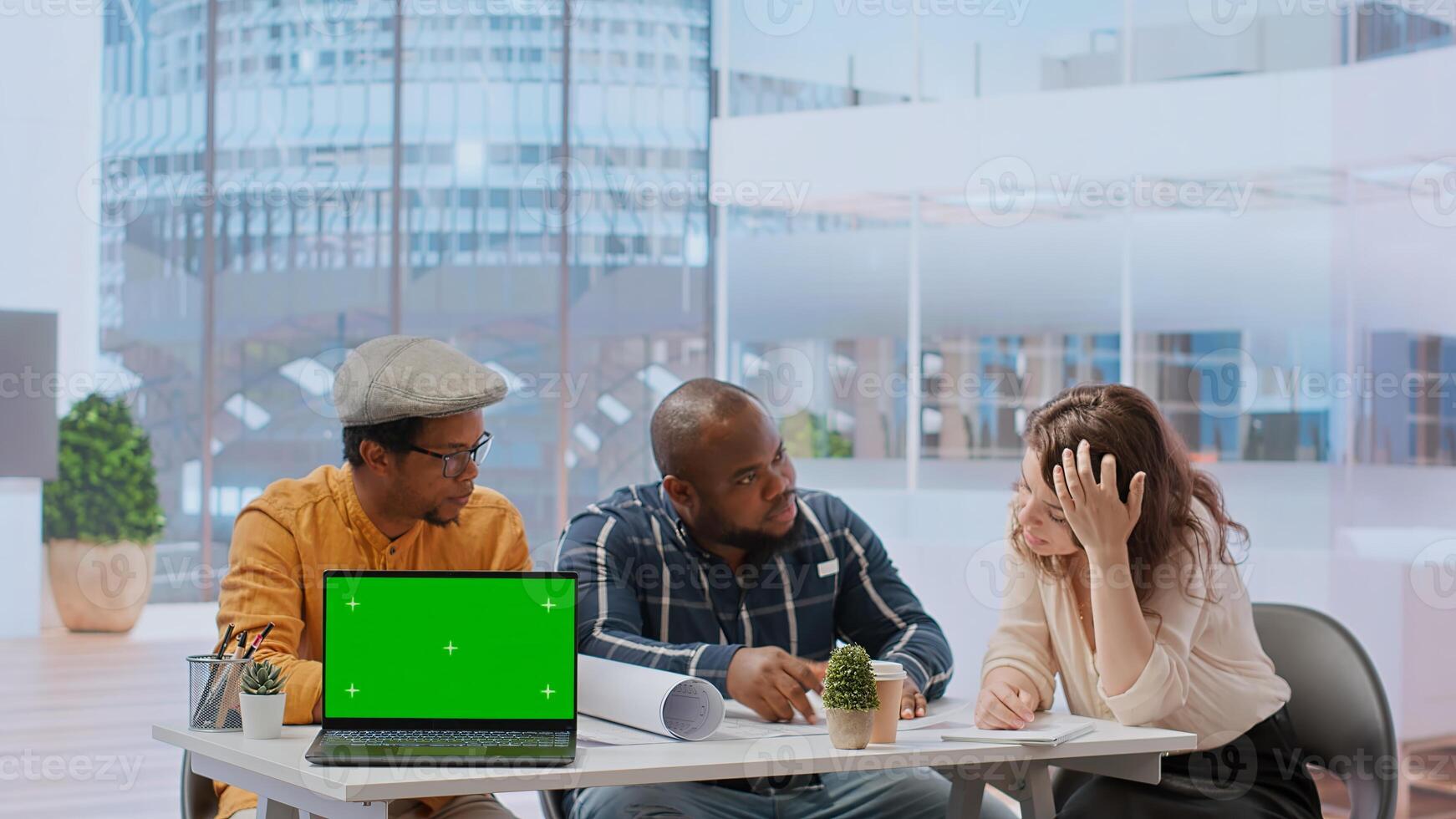 Diverse people meeting on an office tour next to laptop with green screen, realtors presenting the architectural blueprints to client. Businesswoman looking to invest in real estate. Camera B. photo