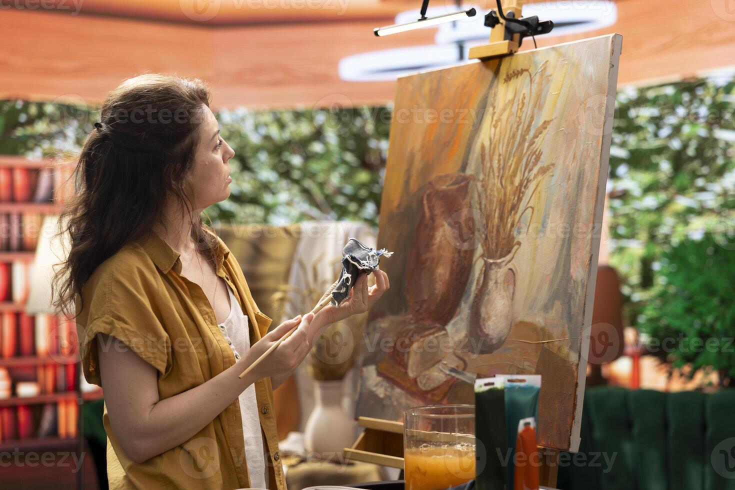 Woman with talent painting a rustic masterpiece and using fabric to clean her brush after changing the color. Artist feeling inspired to try a new painting technique in art and craft workshop. photo