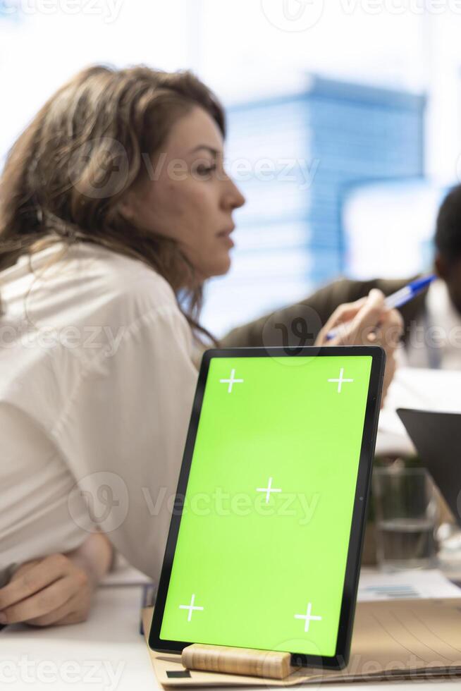 Employees and shareholders using chroma key screen in a corporate briefing, reviewing economic indicators on papers. Business people discussing finance planning and setting strategic goals. photo