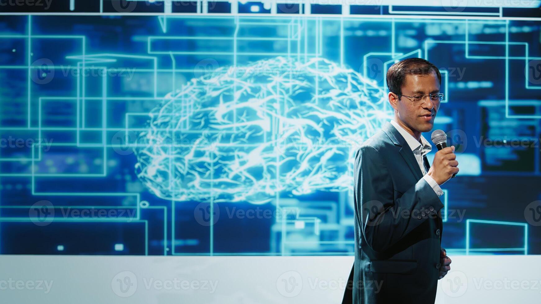 Tech company CEO using summit as platform to launch latest AI products. Manager uses mic to talk at forum to connect with business leaders and investors interested in artificial intelligence, camera B photo