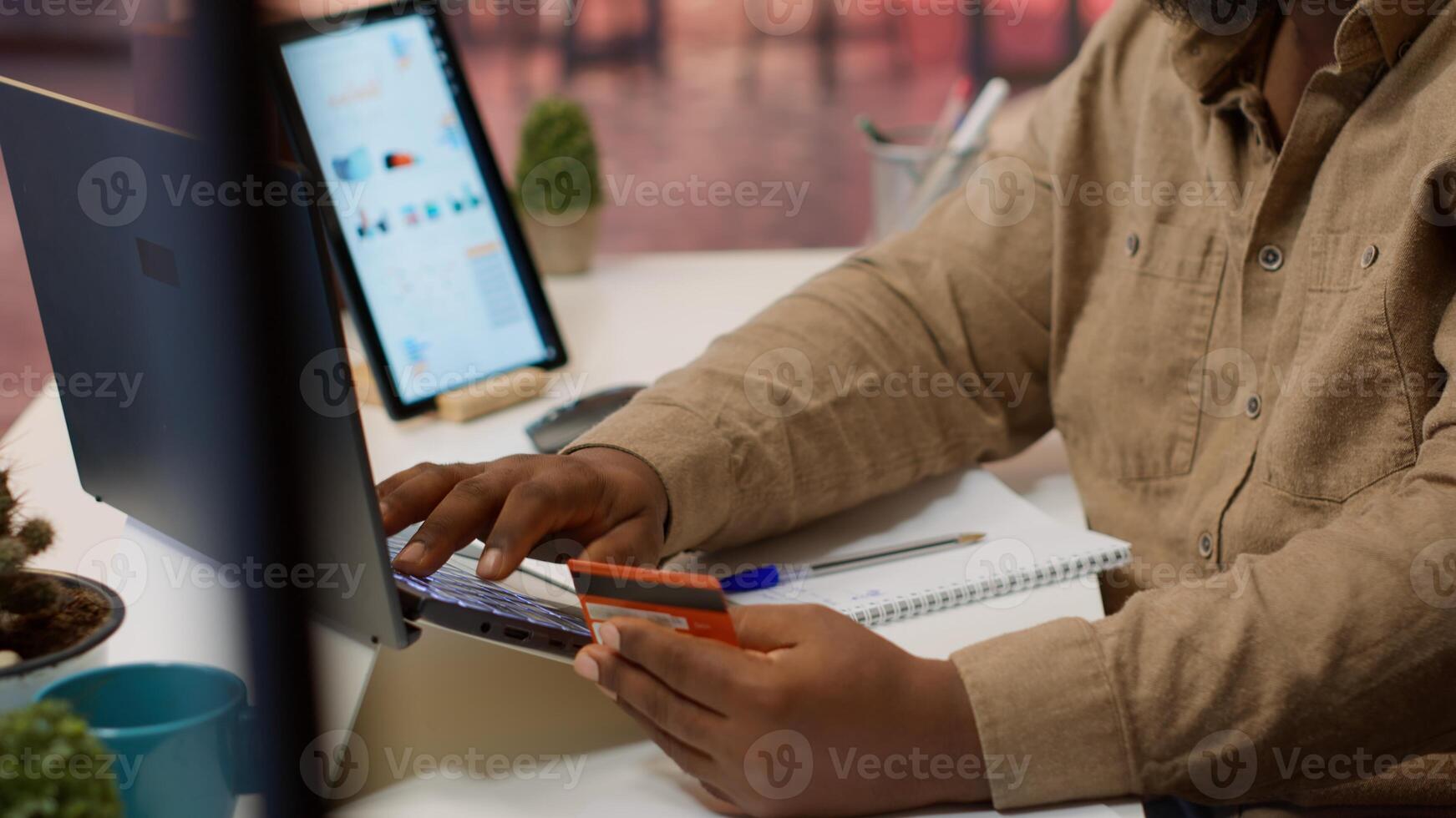 Successful freelancer does online shopping with his credit card, making electronic banking transactions at home office setup. Businessman doing remote work and buying things on laptop. Camera A. photo