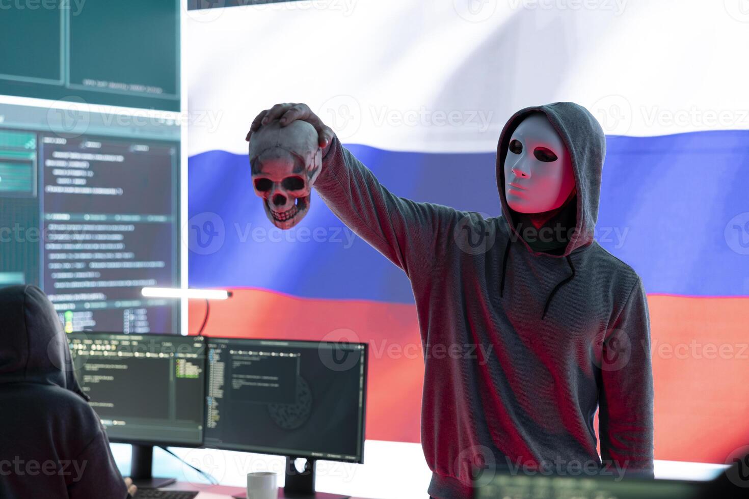 Russian cyber criminal with anonymous mask and hood holding a skull, making death threats and asking for ransom. Dangerous evil person symbolizing cyber threats and cyberterrorism. photo
