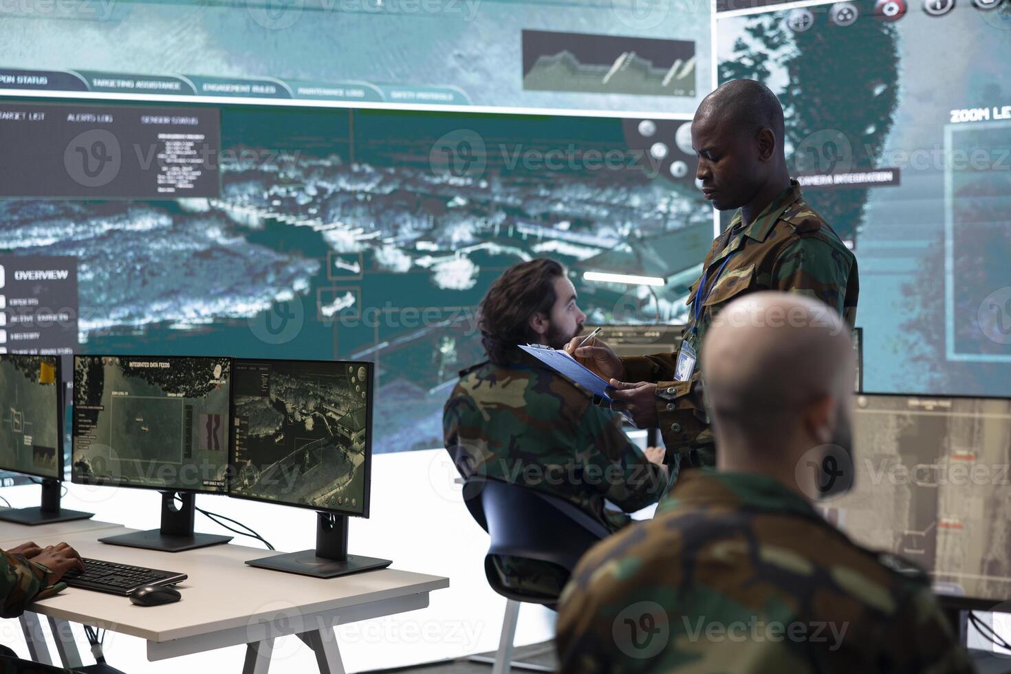 Commander and his squad operating satellite systems via CCTV and radar to track enemy aircraft or other hostile vessels. Military staff uses big screen in command post to guarantee national safety. photo