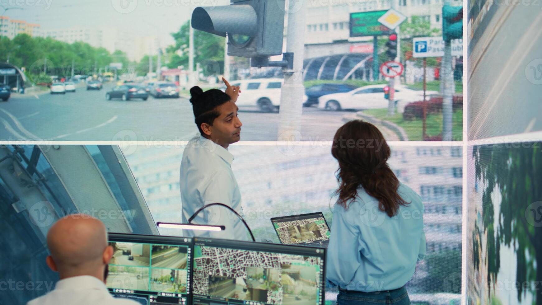 Diverse employees monitoring traffic via radar cameras at stop lights, using surveillance CCTV footage sensors in the city. People tracking cars in the government database, public safety. Camera B. photo