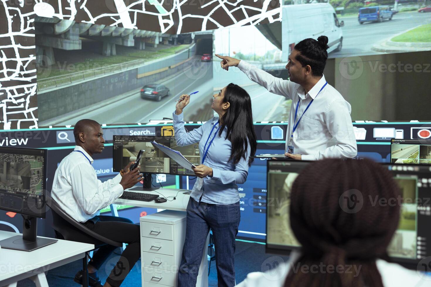 Indian managers instructing their staff how to use CCTV footage and provide gps coordinates to couriers. Monitoring room operators using satellite map for order tracking, cargo surveillance. photo
