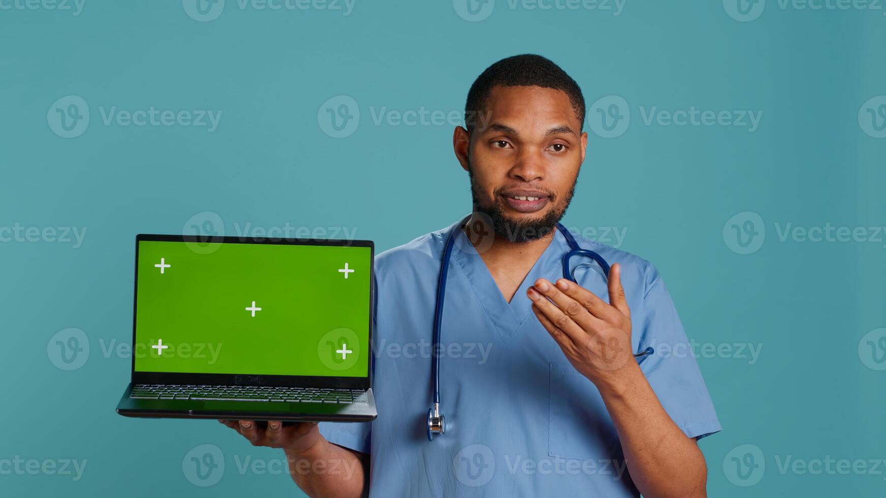 Portrait of african american doctor in medical scrubs using isolated screen laptop. Hospital staff member doing presentation using chroma key notebook, showing patient treatment plan, camera A photo