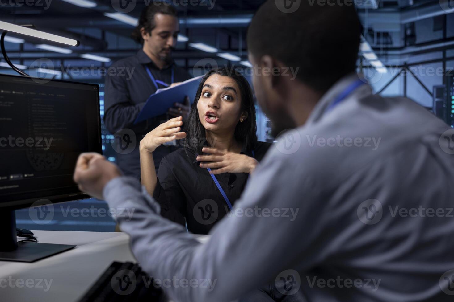 IT staff members in server room ensuring data remains shielded from potential threats. Multiracial coworkers chatting at work while safeguarding data center hardware against malware photo
