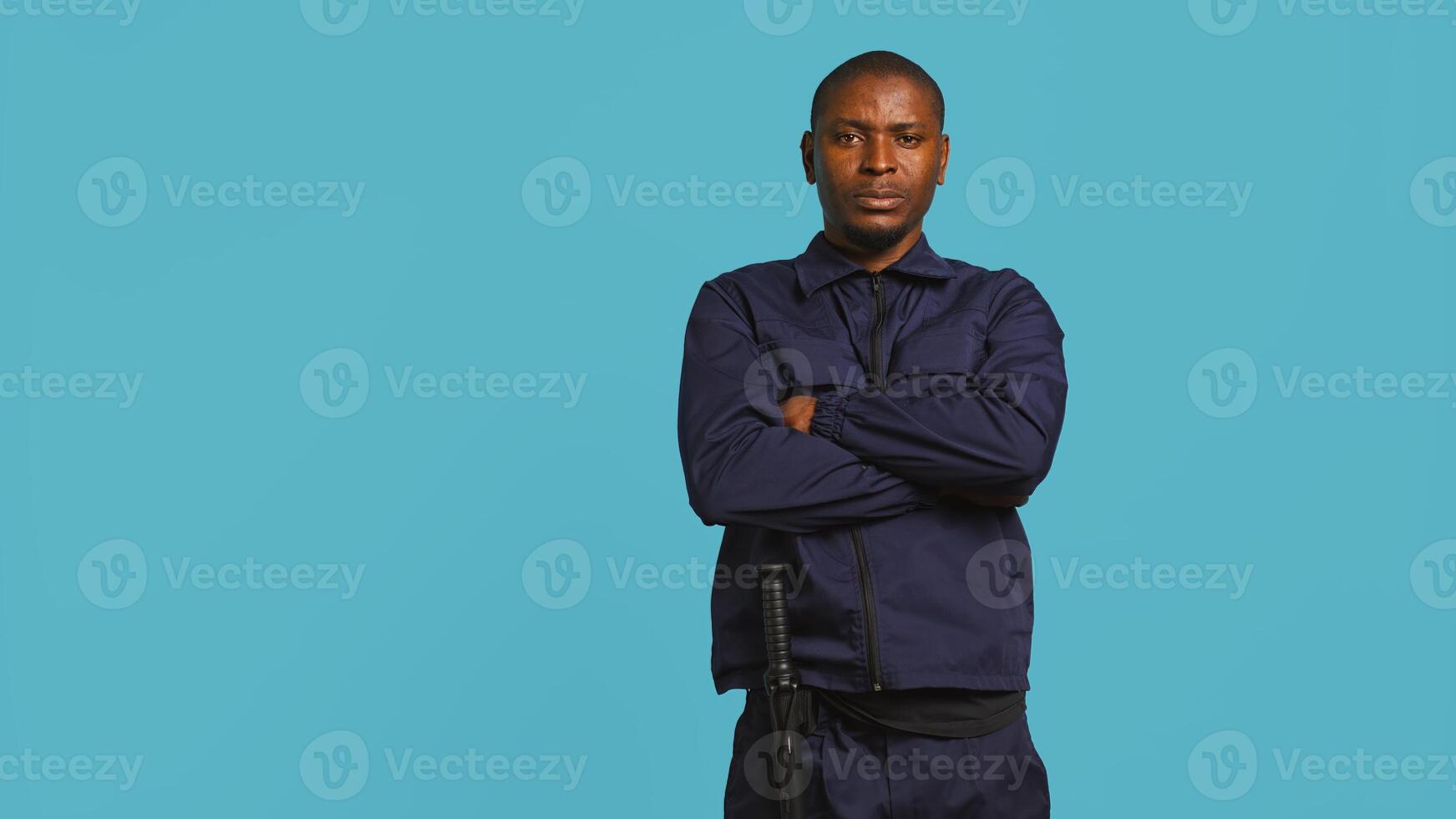 Portrait of smiling security agent securing assigned post, isolated against studio background. African american guardian prepared to handle security breaches and diffuse tense situations, camera B photo
