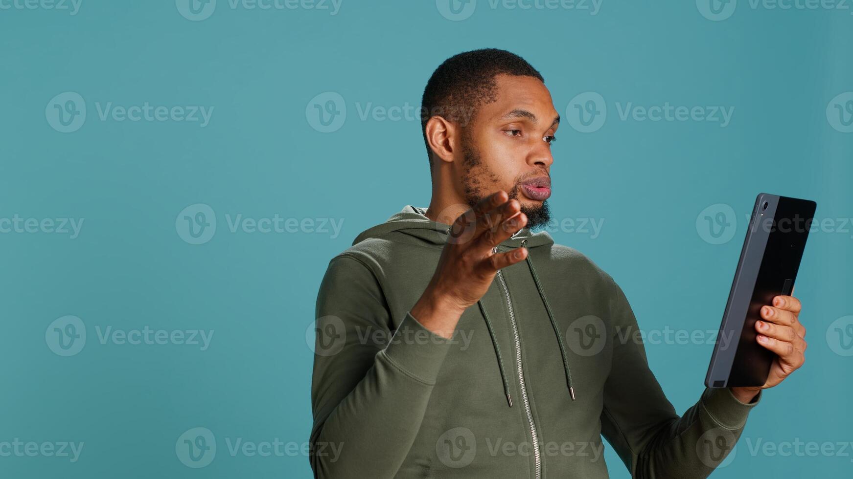 Man having entertaining conversation with friends during videoconference meeting using tablet, studio background. Person interacting with mates during internet videocall on portable device, camera A photo