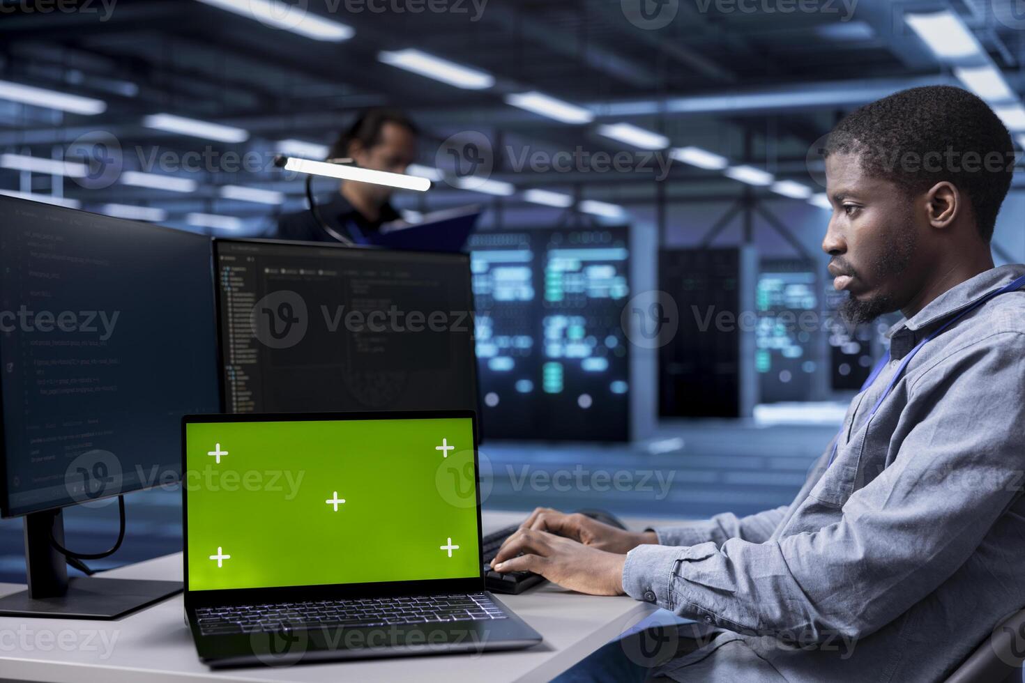 Engineer in data center running system diagnostic tests using isolated screen laptop. African american man in server farm deploying error checking utilities on mockup notebook to repair network issues photo